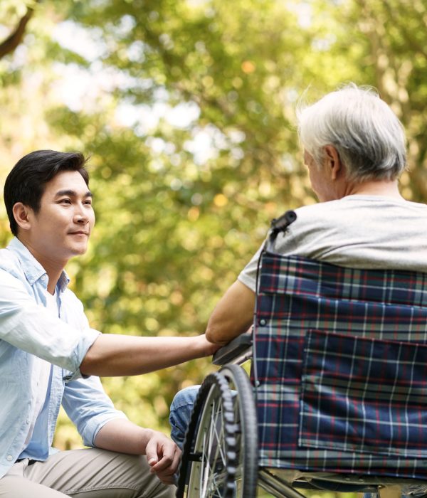 Asian,Son,Talking,To,And,Comforting,Wheelchair,Bound,Father